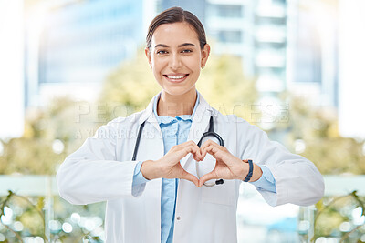 Buy stock photo Smile medical doctor with heart sign hands gesture in modern health clinic or hospital. Happy, positive and wellness young woman healthcare worker or physician with support, love and care symbol