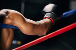 Sports, fight and hand of a boxing man resting in the corner of a boxing ring during an exhibition match, exercise or workout. Motivation, fitness and training boxer relax and tired after fighting