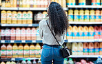 Black woman customer shopping for juice at supermarket or grocery store discount price on healthy fruit brand products. African girl or shopper at beverage shelf to buy sale offer groceries drinks