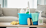 House, cleaning service and container with spray bottle, rubber gloves and scrub in home living room or apartment interior. Spring clean day, career or housekeeping with household products on table