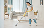 Woman working in a cleaning service mopping the living room floor of a modern home or apartment. Asian cleaner or housewife doing her job or housework to spring clean house for good hygiene lifestyle