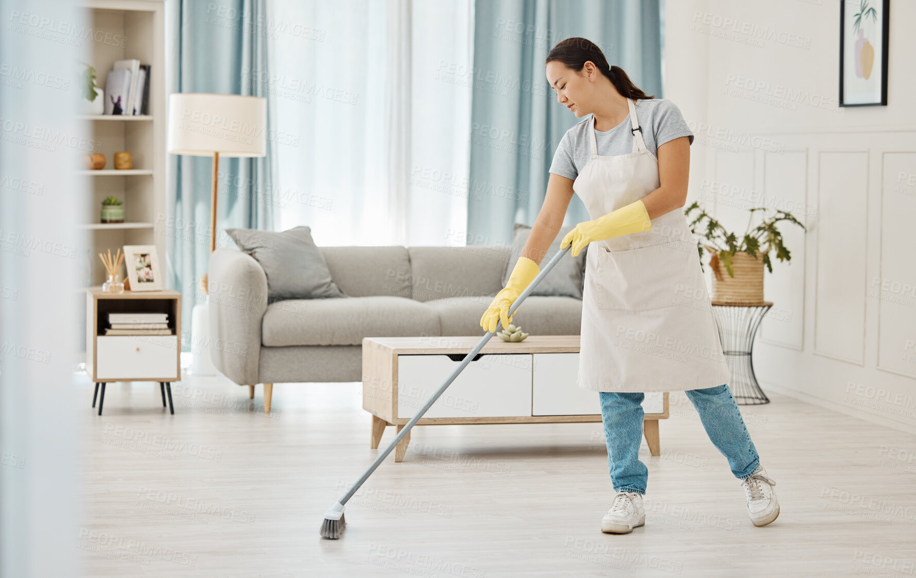 Buy stock photo Woman working in a cleaning service mopping the living room floor of a modern home or apartment. Asian cleaner or housewife doing her job or housework to spring clean house for good hygiene lifestyle