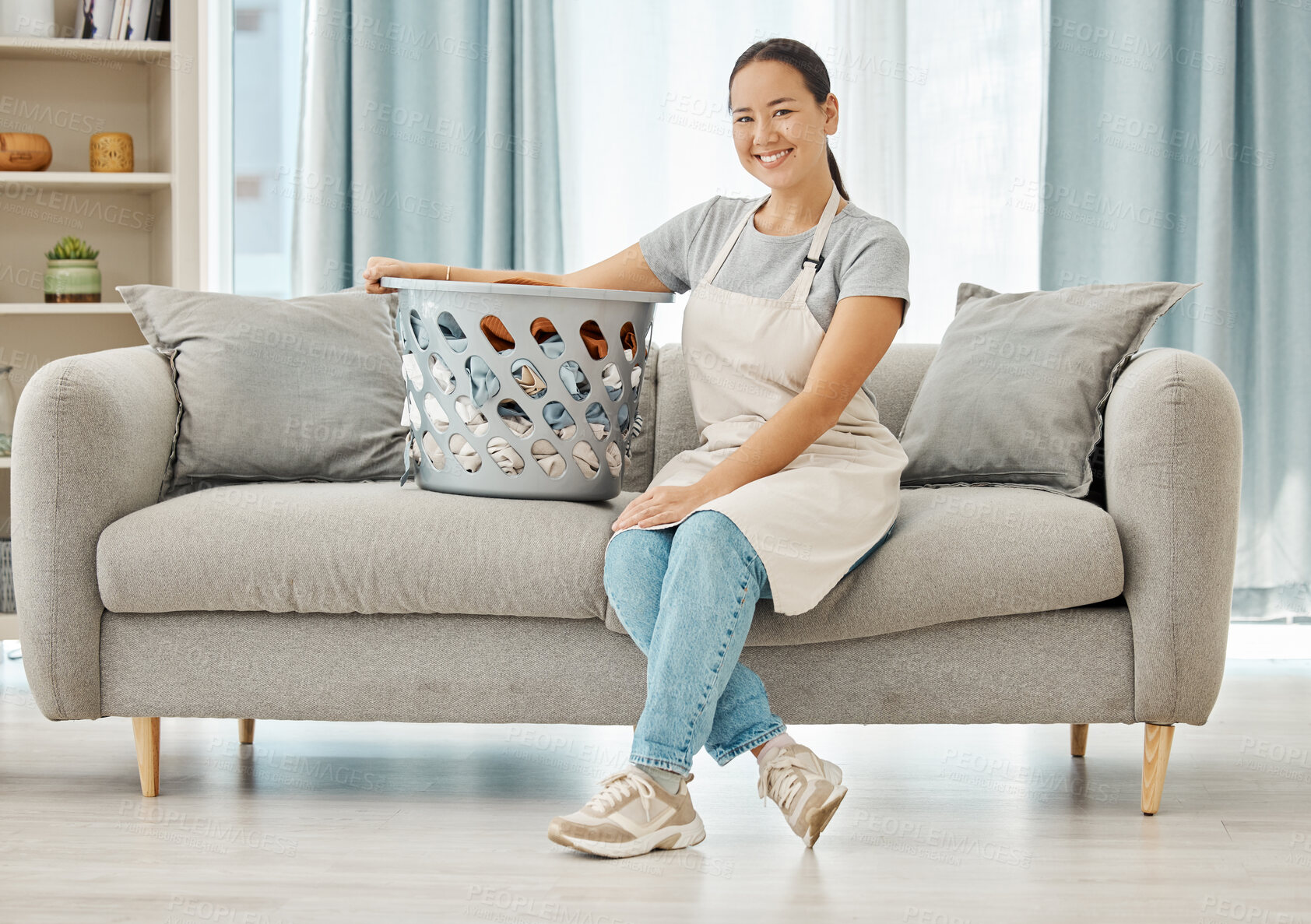 Buy stock photo Cleaning laundry, service and home woman working to clean basket of clothes, living room sofa and house linen in an apartment. Portrait of Asian cleaner staff in lounge doing housekeeping with smile