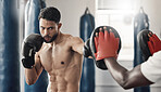 Boxing pad, sports man and gym exercise coaching with personal trainer expert for tournament. Strong, muscular and tough mma athlete doing fitness practice for wellbeing and punch discipline.