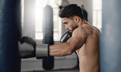 Buy stock photo Training, fitness and workout man boxer, sweating and doing a cardio exercise at the gym. Sporty, sweaty and determined male athlete punching a bag at a sports boxing center for health and wellness