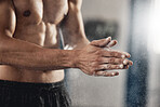 Muscular man rubbing sports chalk on his hands in the gym during his fitness training or workout. Closeup of a guy with an active, healthy and wellness lifestyle preparing for his exercise routine.