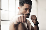 Energy, power and boxing by athletic man fist punch in a gym or fitness studio. Portrait of a boxer workout or exercise, endurance and speed preparation before a kickboxing, competitive match