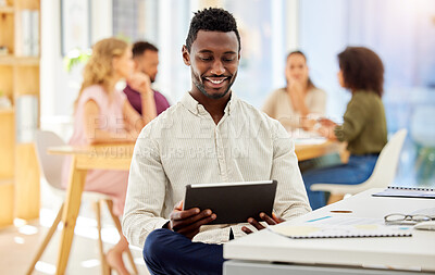 Buy stock photo African businessman working on a digital tablet while sitting by his desk in a corporate office. Happy, professional and black man doing research on the internet or a website with a mobile device.