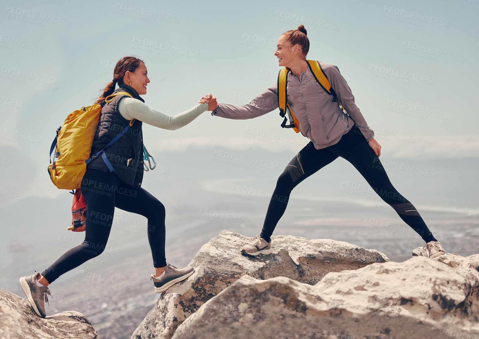 Buy stock photo Happy women help while hiking up a rocky mountain in nature with backpack. Females friends exercise in nature park climbing and jumping while with sportswear training or trekking together outdoors