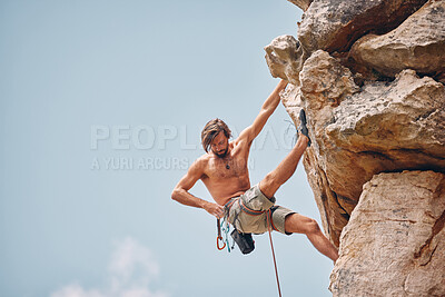 Buy stock photo Mountain or rock climbing, cliff hanging and adrenaline junkie out on adventure and checking his safety equipment, hook and rope. Fearless man doing fitness, exercise and workout during extreme sport