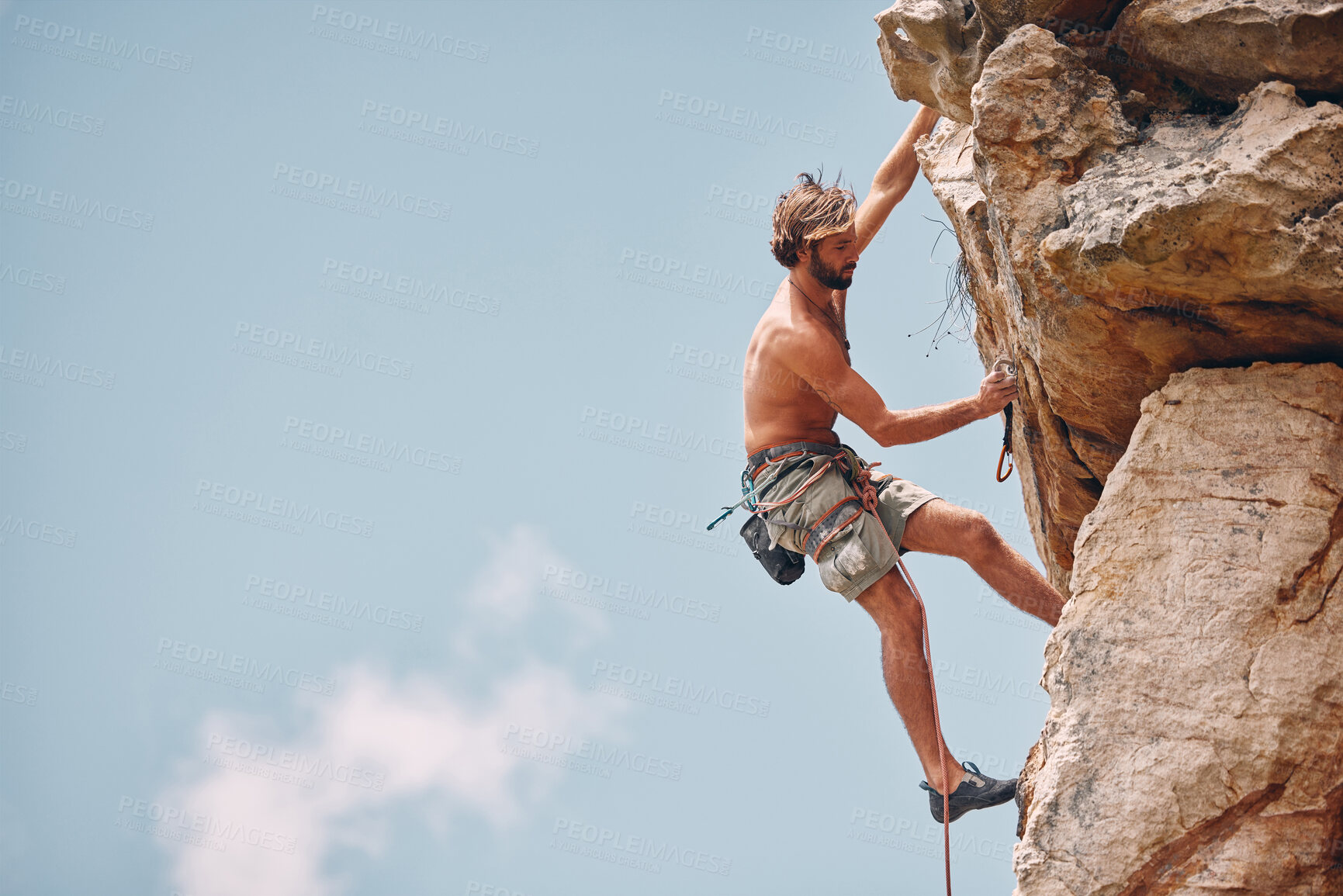 Buy stock photo Man mountain or rock climbing while cliff hanging and adrenaline athlete on adventure and check safety equipment, hook and rope. Fearless man doing fitness, exercise and workout during extreme sport