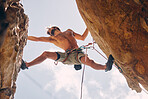 Fitness, rock climbing and strong mountain climber on a cliff with ropes in summer challenge and extreme exercise. Danger, courage and healthy man fearless, sports and training on big rocks or stone