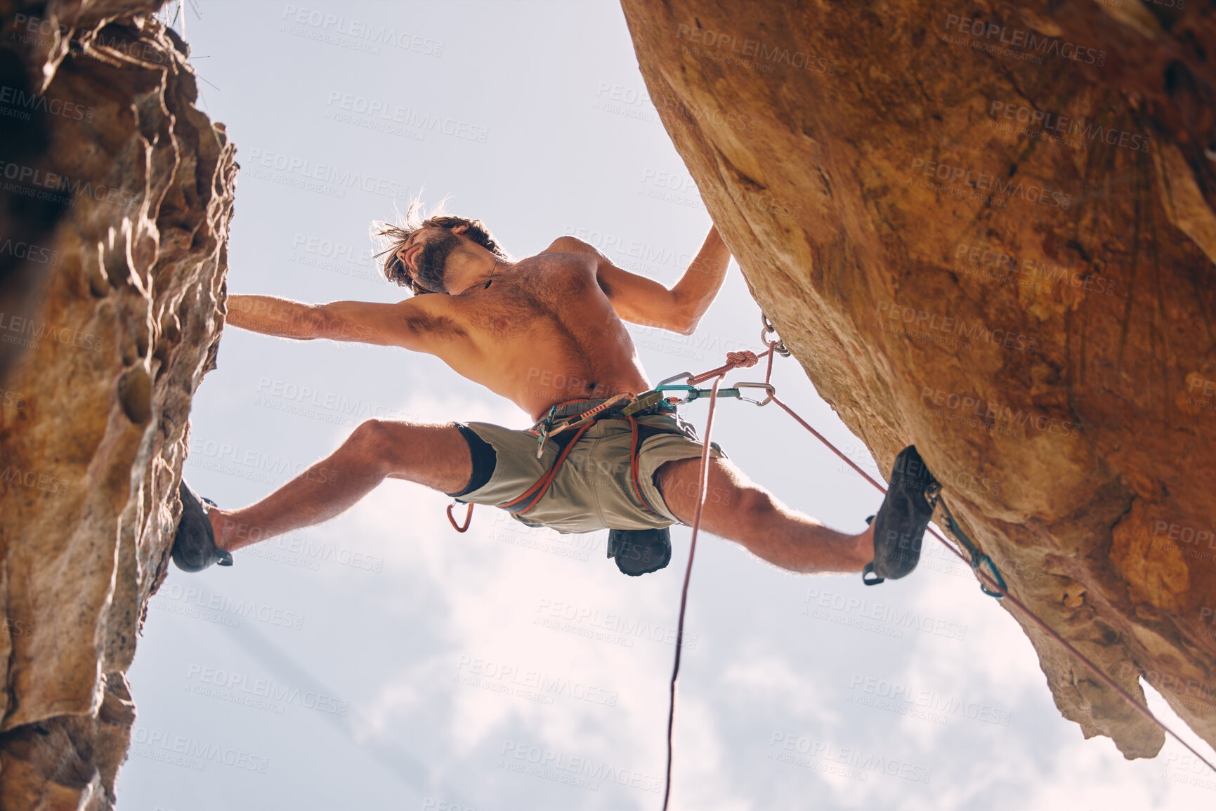 Buy stock photo Fitness, rock climbing and strong mountain climber on a cliff with ropes in summer challenge and extreme exercise. Danger, courage and healthy man fearless, sports and big rocks or stone below view