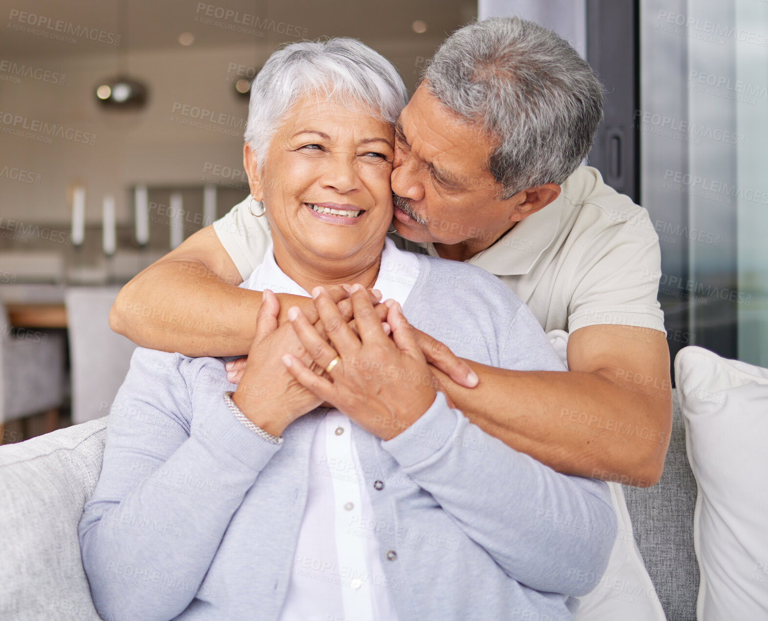 Buy stock photo Happy senior couple kiss on sofa and smile for love, happiness and trust in family home or house living room. Elderly Mexico man and woman or people in retirement hug, kissing and romance on couch