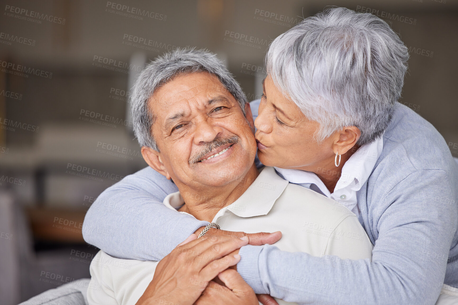 Buy stock photo Happy Mexico senior couple kiss on living room sofa for love, care and trust in romantic relationship at house or home. Elderly people or retirement man and woman smile, hug and kissing face cheek