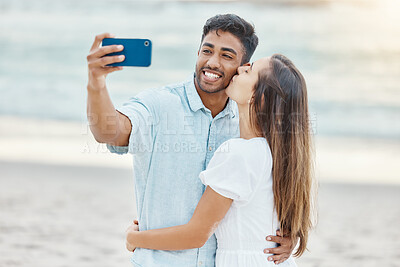 Buy stock photo Travel, vacation and selfie by couple kiss on a beach holiday, bonding and having fun on seaside getaway. Young man and woman embrace, enjoying their relationship and romance on a romantic trip