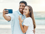 Love, beach and engaged couple taking a selfie on a phone while on a romantic summer vacation. Happy woman showing off her wedding ring while taking a picture with her husband on honeymoon holiday.