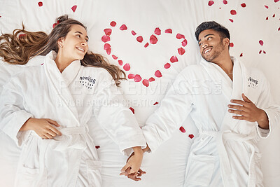 Buy stock photo Man and woman married couple on luxury bed celebrate honeymoon, love and relax in romantic vacation spa hotel. Happy, marriage and young people smile on valentines day with rose heart in bedroom