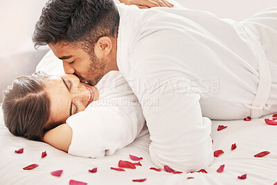 Buy stock photo Hotel, happy and love couple on a holiday for a romantic anniversary trip with happiness. Kiss, hug and passion of young lovers smile on a bed of rose petals in a bedroom together with happiness 