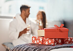 Christmas gift, present and happy couple celebrate the holiday at hotel with champagne. Love, happiness and vacation celebration of a girlfriend and boyfriend smile and drink in a bedroom together