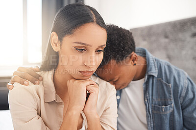 Upset couple fighting, arguing or breaking up while sitting on their bed in the bedroom at home. Sad man crying on the shoulder of his thinking wife while talking about divorce or difficult problems.