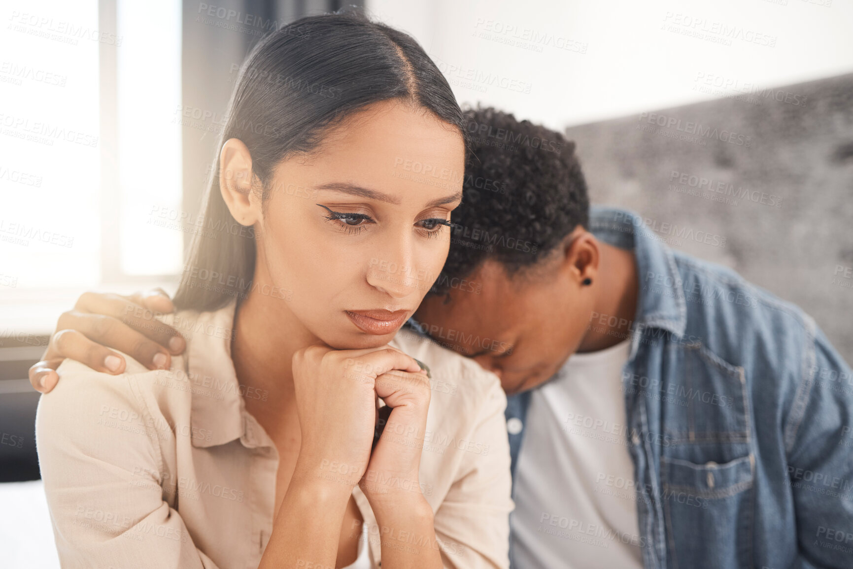 Buy stock photo Upset couple fighting, arguing or breaking up while sitting on their bed in the bedroom at home. Sad man crying on the shoulder of his thinking wife while talking about divorce or difficult problems.