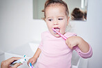 Baby learning to brush her teeth, dental and oral hygiene. Toothbrush, toothpaste and brushing teeth in child development and routine. Dentist, dentistry and teeth cleaning in young children. 