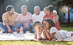 Secret, sister and children with a girl whispering to her sibling and a black family in the background. Kids, mystery and gossip with a female child being secretive on a picnic in the park in summer