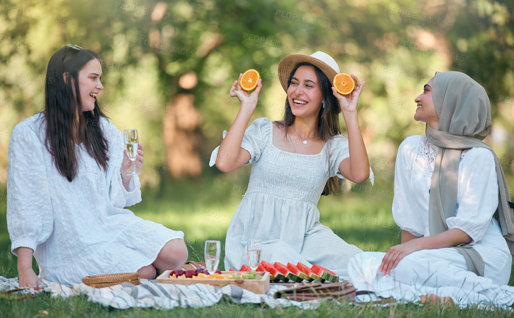 Buy stock photo Diversity, Islamic and friends on a fruit picnic on grass in nature enjoying orange, watermelon and fun jokes. Muslim, smile and happy women laughing and smiling together at a natural park for lunch