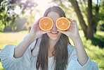 Woman, orange slice and eye pose in outdoor park with natural summer sunshine ray flare. Young caucasian girl holding healthy, juicy and organic citrus fruit for fun posing moment outside.