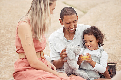 Buy stock photo Interracial family, beach travel and summer fun with child enjoying bonding time with mother and father during a picnic on rocks. Happy man and woman playing on vacation or holiday with cute daughter