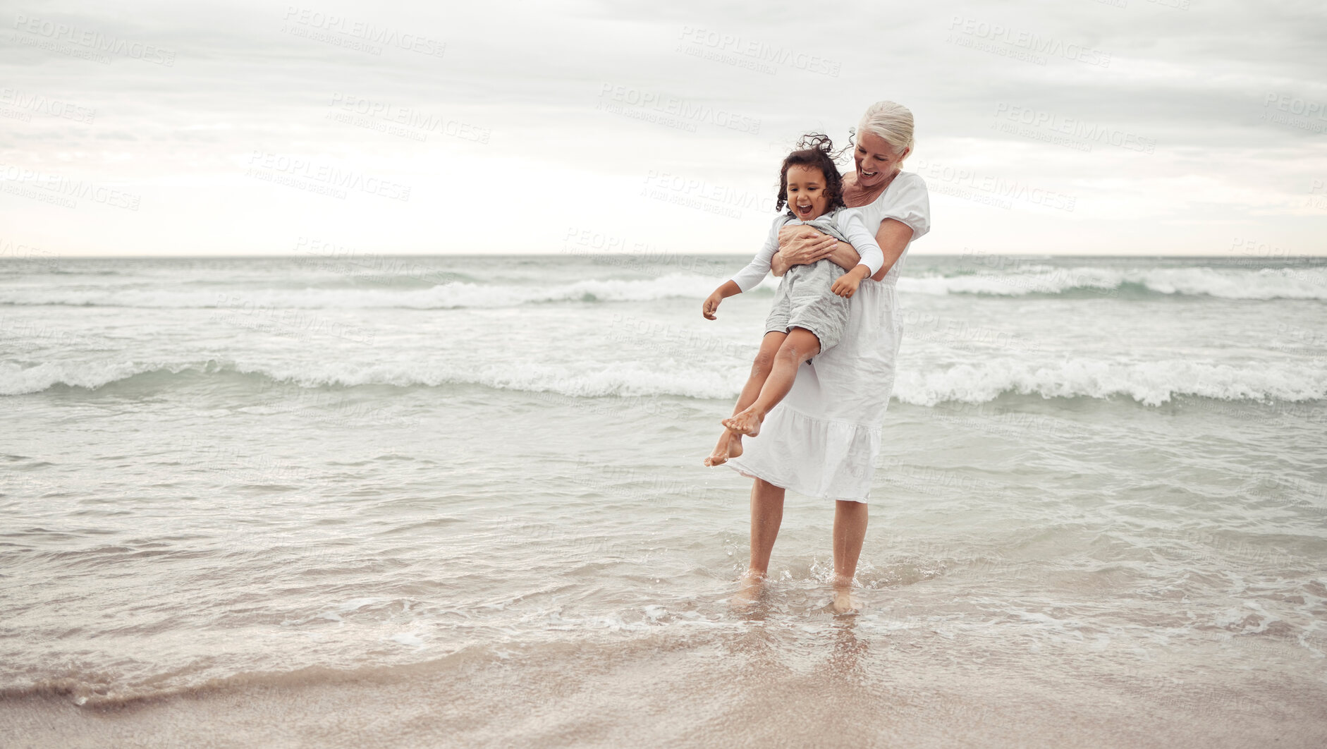 Buy stock photo Grandmother, beach fun and child in happy bonding time together outside in nature. Elderly woman holding little girl in playful family bond at the ocean on holiday vacation in the outdoors