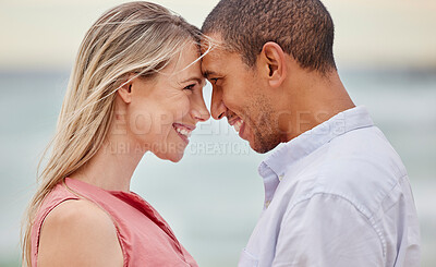 Buy stock photo Portrait of couple at the beach with their forehead touching. Multiracial man and woman in relationship, happy, smiling and in love on vacation. Bonding, love and quality time together
