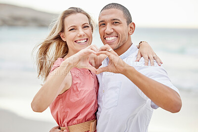 Buy stock photo Happy interracial couple show heart sign with their hands and enjoying fresh air on vacation at the beach while bonding. Portrait of couple hugging at ocean with smile and love together on holiday