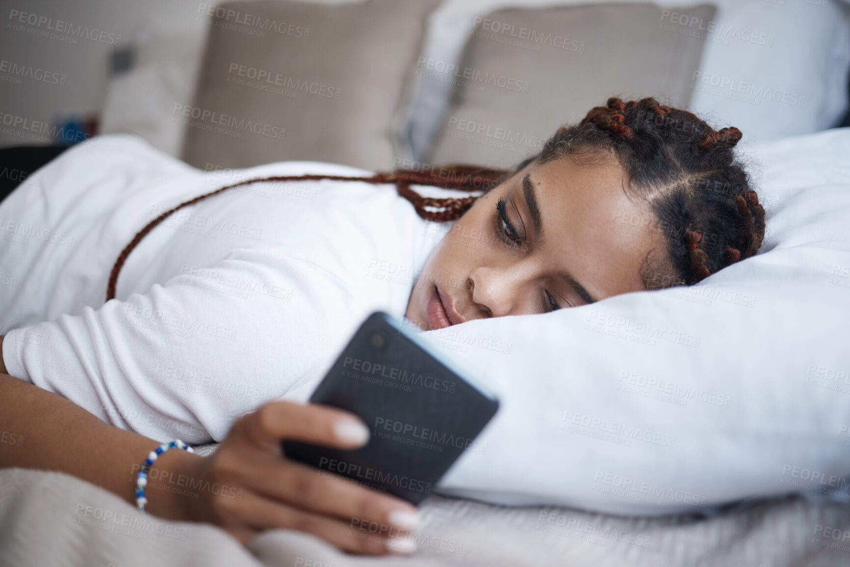 Buy stock photo Depression, sad and african woman on a phone relaxing on the bed in her bedroom at home. Tired, mental health and lonely black girl browsing on social media or internet while having breakup problems.