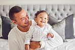 Father, happy and relax with baby in bedroom, family home and house for bonding, relax and playful morning together. Dad care, love and happiness to cute, smile and child, kid and toddler development