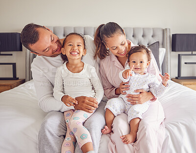Buy stock photo Happy, smiling and a family in pajamas on bed with small girls. Young mother and father with girl children in bedroom in the morning. Love, smile and parents with kids spending time together at home