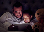 Man, child and digital tablet streaming movies, cartoon or game in bed at night. Happy father and son browsing the internet, online or web with social media app while watching a comedy in the bedroom