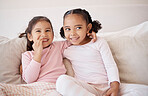Family, children and bonding by sisters on a sofa, laugh and relax while sharing a secret in a living room. Happy, play and cheerful girls enjoying a fun morning together, looking sweet and cute