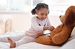 Black child doctor with a teddy bear on her bed, she holding a stethoscope to its chest and thinking of kid in the hospital. Jobs as a physician, registered nurse and medical assistant are in demand 
