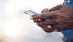 Hands of an african man on a phone networking, doing research on the internet or typing a message. Closeup of a black guy browsing on social media, mobile app or a online website with a smartphone.