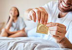 Condom, sex and safety for sexual couple in bed together happy, smile and use protection. Happiness, love and man and woman open birth control contraceptive package to protect against std, sti or hiv
