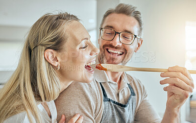 Buy stock photo Happy couple cooking, tasting spoon of food and meal, lunch and dinner in kitchen at home. Smile mature man giving hungry woman a taste of homemade tomato sauce meal in mouth to enjoy eating together