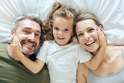 Buy stock photo Portrait of family home, girl and parents on bed for fun morning, relax lifestyle and happiness. Above of smile mom, happy dad and playful kid child face together in bedroom for love, care and joy