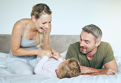 Buy stock photo Happy family play and laugh together on the bed having fun at home on a weekend. Playful, love and carefree parents, mother and father bonding with their daughter, child or kid in the bedroom
