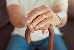 Hands of elderly man with a cane for help, support and walking assistance while relax on living room sofa. Wedding ring hand of widow, senior and retirement person sitting on couch with walking stick