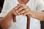 Hands of an elderly woman on a walking cane in a disability nursing or retirement home. Closeup of a disabled senior lady sitting with her stick at a wellness, healthcare or physical therapy center.
