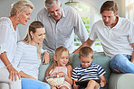 Popcorn, tablet and happy family on sofa watch funny entertainment movie or streaming kids cartoon film online. Parents, grandparents and children on digital mobile app together in family home lounge