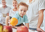 Health, family and baby with orange nutrition for healthy diet, vitamins and minerals on kitchen table at home. Food, fruit and apples for cute child growth and wellness with grandparents and parent.