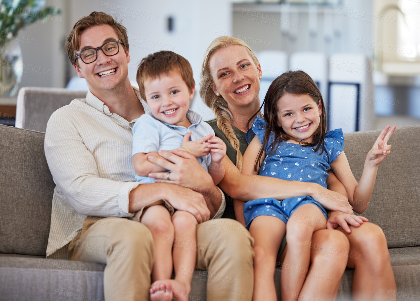 Buy stock photo Family, smile and love of children on lap of mom and dad sitting on the sofa at home for bonding, fun and joy. Man, woman and boy and girl kids sitting together for leisure and showing peace sign